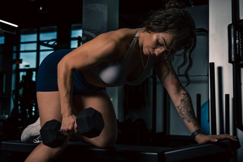 woman in sportswear lifting dumbbell inside a gym